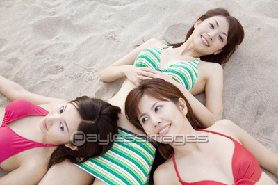 砂浜で寝転ぶ水着姿の女性