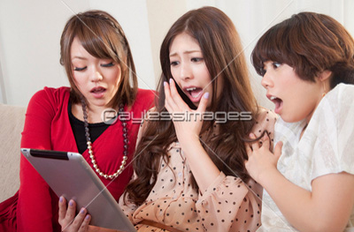 タブレットPCを見ながら笑う女性3人