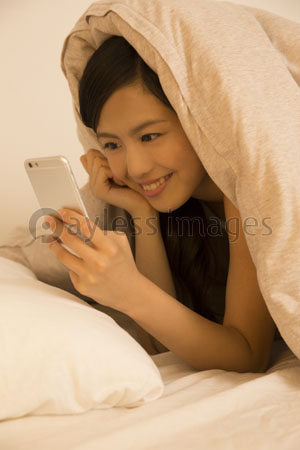 寝転んでスマホを見る女性 商用利用可能な写真素材 イラスト素材ならストックフォトの定額制ペイレスイメージズ