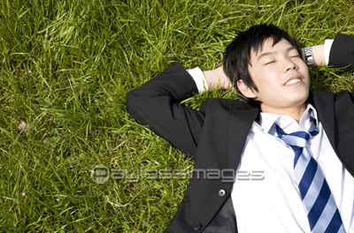 芝生で寝転ぶビジネスマン