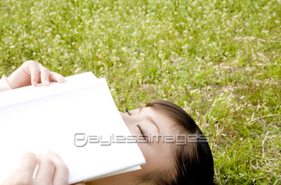 芝生に寝転び本を読む女性