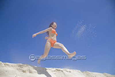 砂浜でジャンプする水着女性 ストックフォトの定額制ペイレスイメージズ