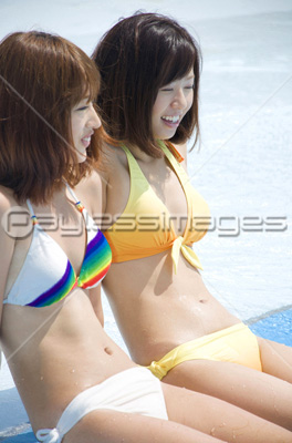 プールサイドに座る水着姿の女性2人