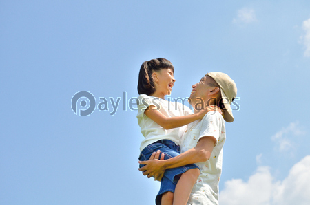 青空で抱っこする親子 ストックフォトの定額制ペイレスイメージズ