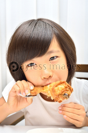 フライドチキンを美味しそうに食べる女の子 商用利用可能な写真素材 イラスト素材ならストックフォトの定額制ペイレスイメージズ