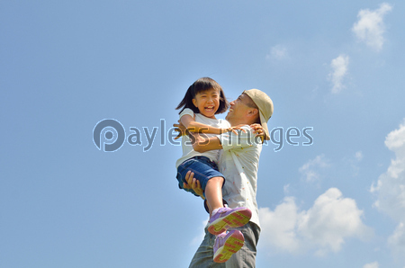 青空で抱っこする親子 夏 ストックフォトの定額制ペイレスイメージズ