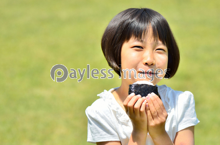 芝生広場でおにぎりを食べる女の子 ストックフォトの定額制ペイレスイメージズ