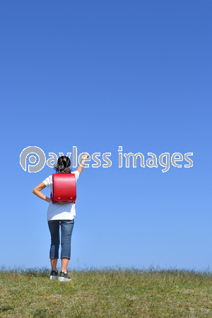 青空でガッツポーズをする小学生の女の子 後姿 ストックフォトの定額制ペイレスイメージズ