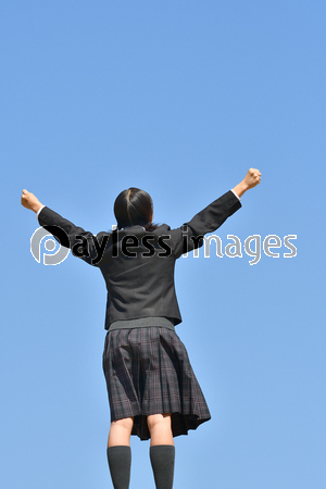 青空でガッツポーズをする小学生の女の子 後姿 ストックフォトの定額制ペイレスイメージズ