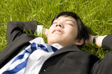 芝生で寝転ぶビジネスマン