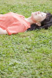 公園の芝生に仰向けに寝転がる女性