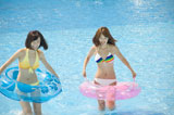 浮輪を持ってプールで遊ぶ水着女性2人
