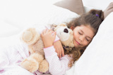 Girl lying on bed with teddy bear